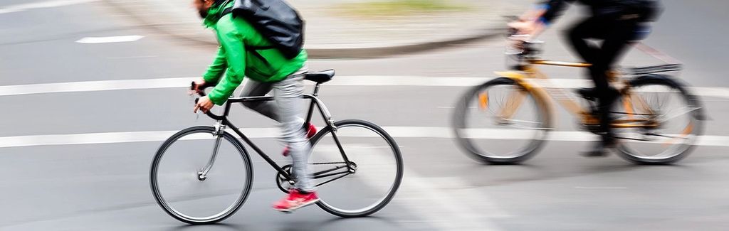 Zwei Fahrräder sind zu sehen, die im Stadtverkehr fahren. Das Foto hat Unschärfen