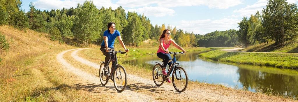 Junges glückliches Paar fährt mit dem Fahrrad am Fluss entlang