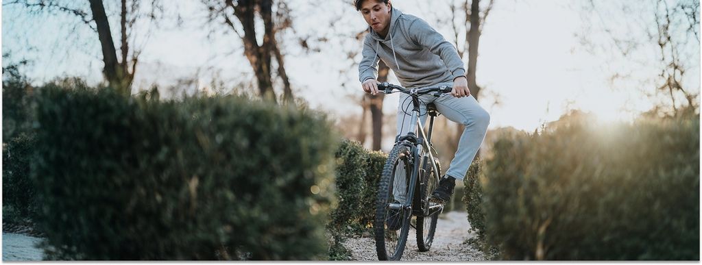 Ein junger Erwachsener hält mit Mühe das Gleichgewicht auf seinem Fahrrad im Park.