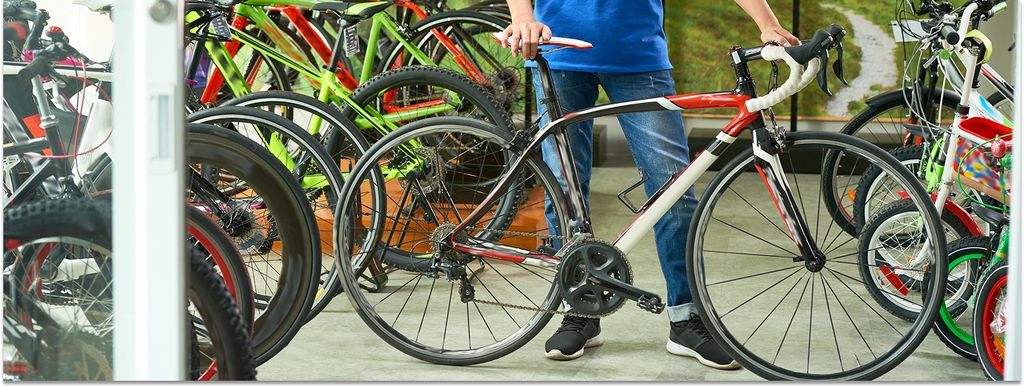 In einem Fahrradladen wird ein Rennrad präsentiert, links und rechts stehen weitere Fahrräder für Kinder und Erwachsene.