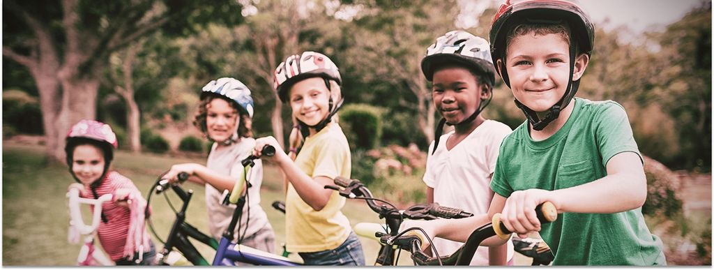 Fünf Kinder mit Fahrradhelm auf ihren Fahrrädern in einer Reihe nebeneinander