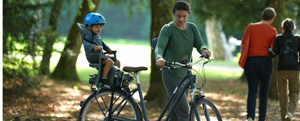 Frau mit E-Bike und Kleinkind im Fahrradkindersitz